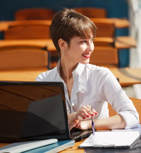 Mujer sonriente trabajando con un portátil en un espacio exterior soleado