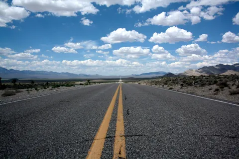 Carretera recta atravesando un paisaje desértico bajo un cielo con nubes, simbolizando un camino por recorrer