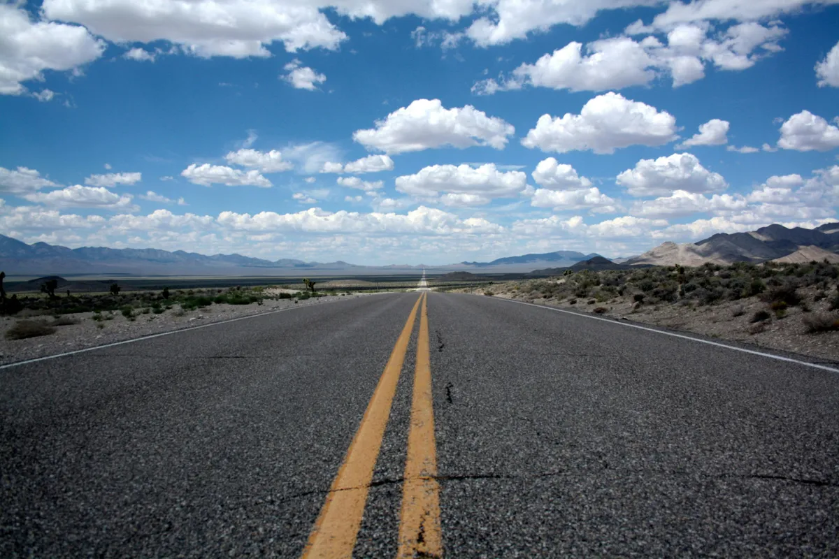 Carretera recta atravesando un paisaje desértico bajo un cielo con nubes, simbolizando un camino por recorrer
