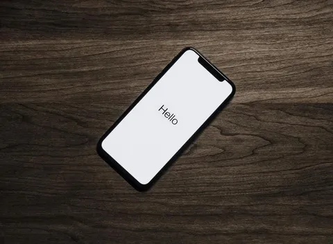 Smartphone con la pantalla de bienvenida encendida sobre una mesa de madera